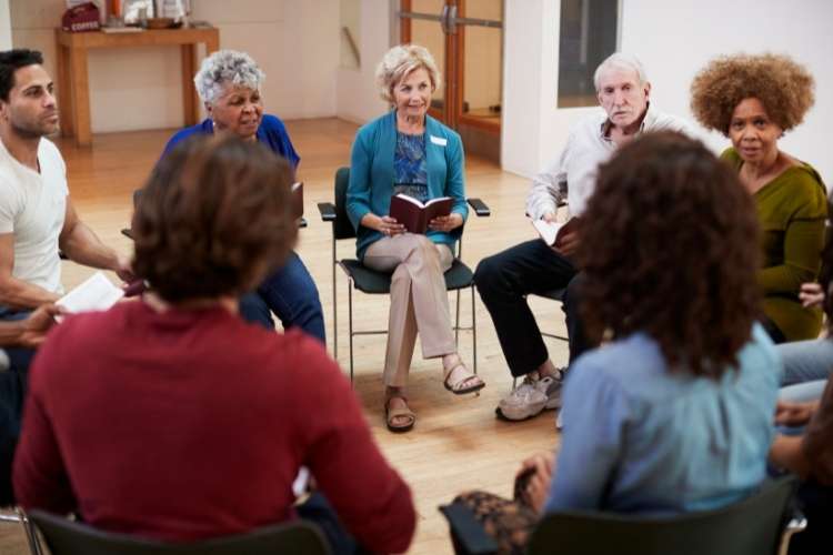 Grupo de adultos sentados em círculos, na igreja, trocando vivências.