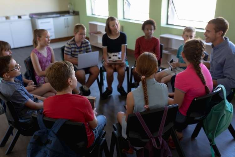 Crianças sentadas em roda no Ministério Infantil, com professor explicando a atividade.
