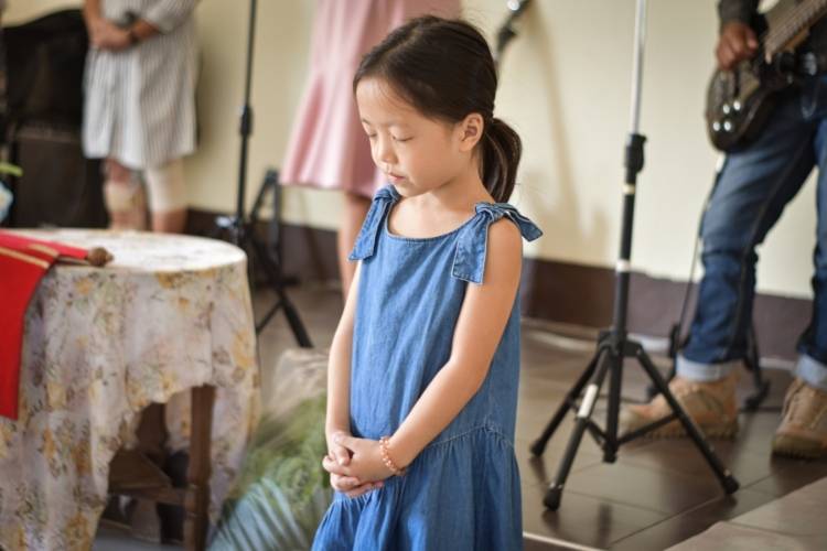 Menina orando durante o culto.