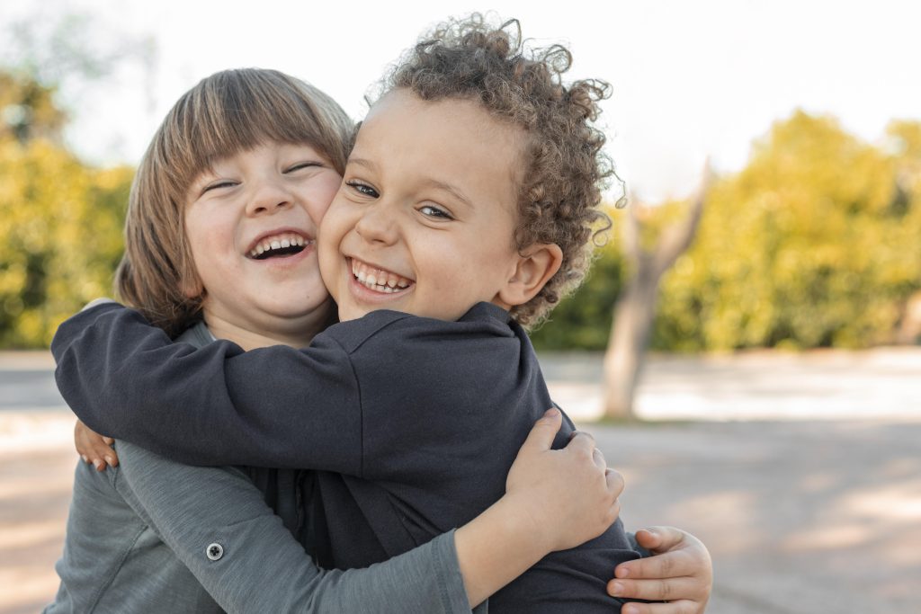 Dois meninos crianças se abraçando sorridentes.