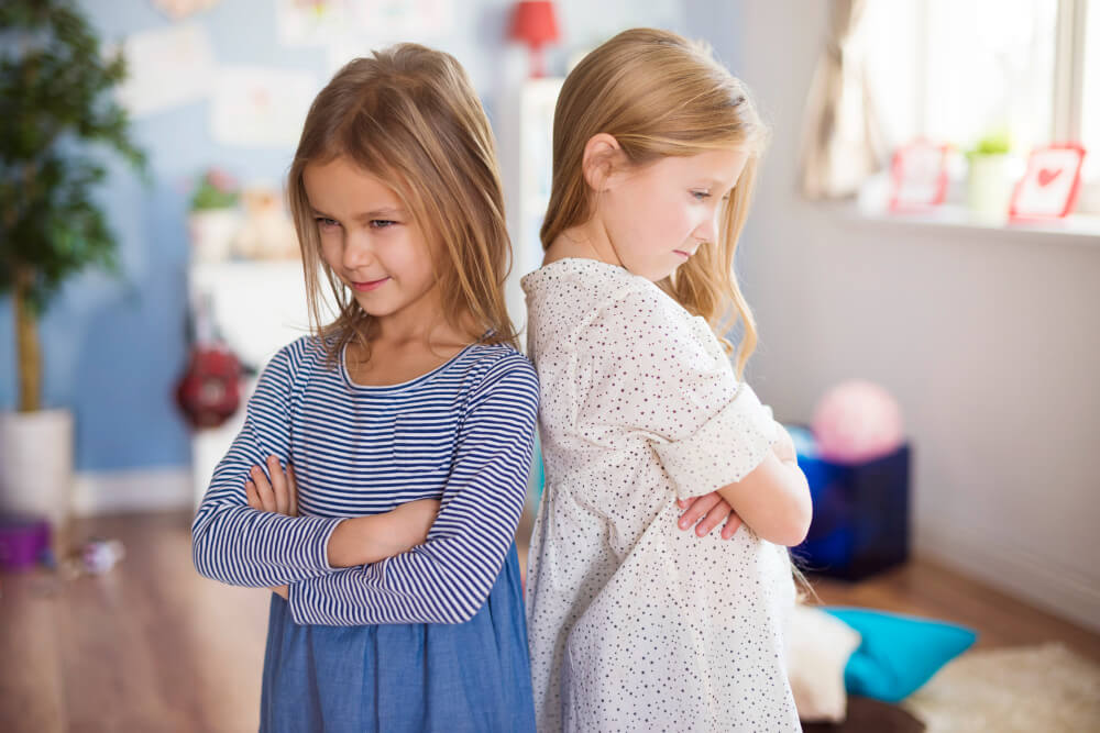 Duas meninas de costas uma para a outra com expressão de desentendimento, representando conflitos e desafios ligados ao bullying na igreja.
