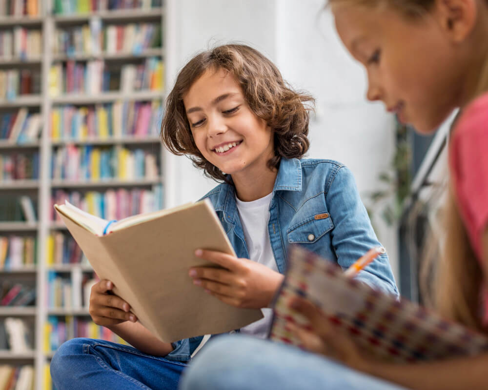 Duas crianças lendo felizes em uma biblioteca, simbolizando o aprendizado e a fé transmitidos por meio de livros cristãos para crianças.