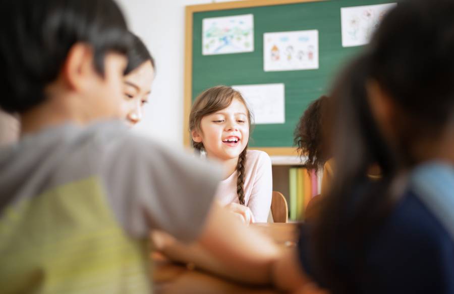 Grupo de crianças interagindo em aula bíblica infantil com atividades em sala de ensino cristão.