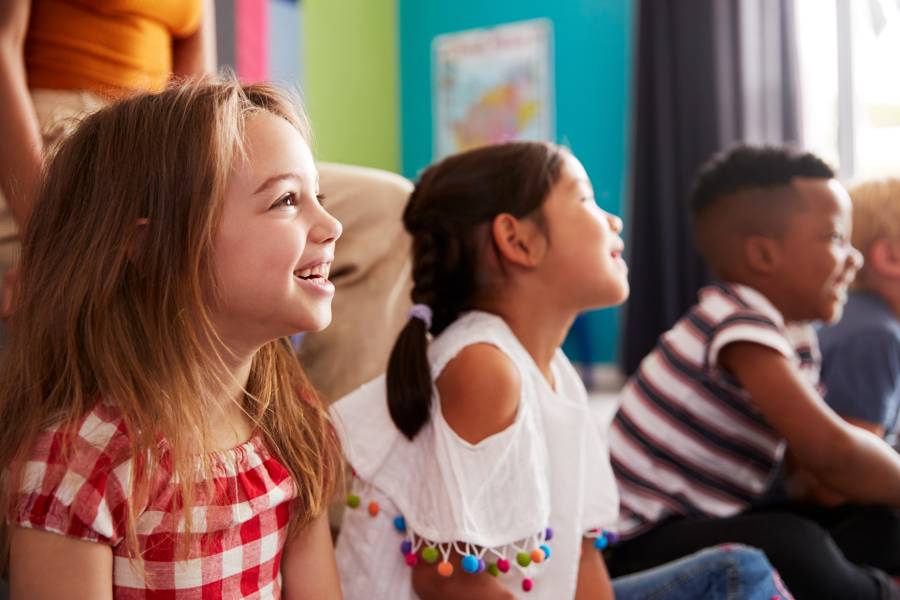 Crianças sorridentes e atentas em sala de aula, representando o ambiente seguro pela checagem de antecedentes criminais no Ministério Infantil