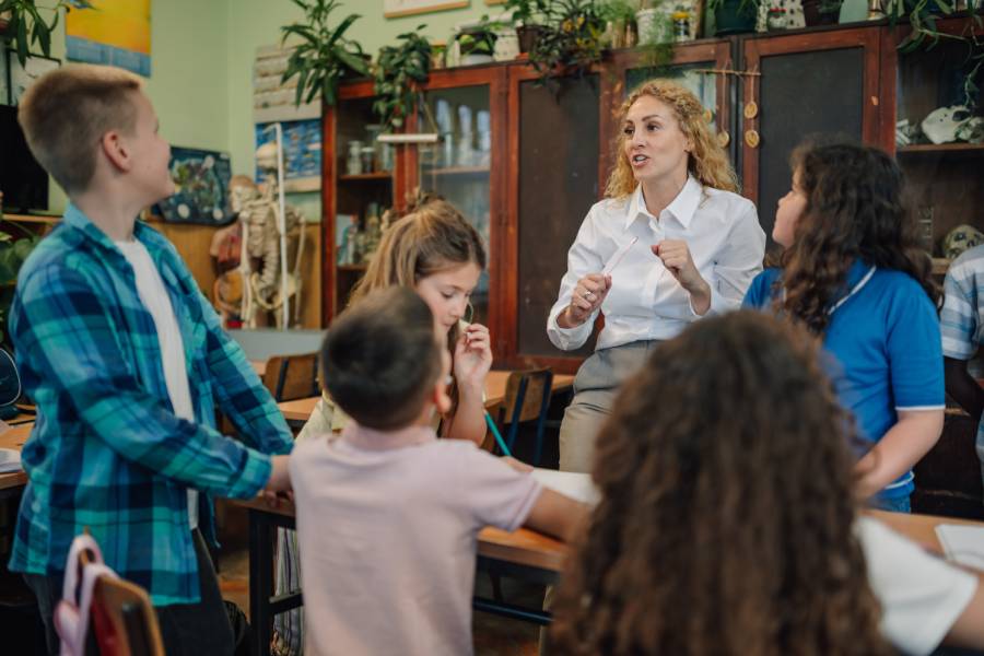 Professora conversando com crianças em sala de aula, representando o ambiente seguro pela checagem de antecedentes criminais no Ministério Infantil